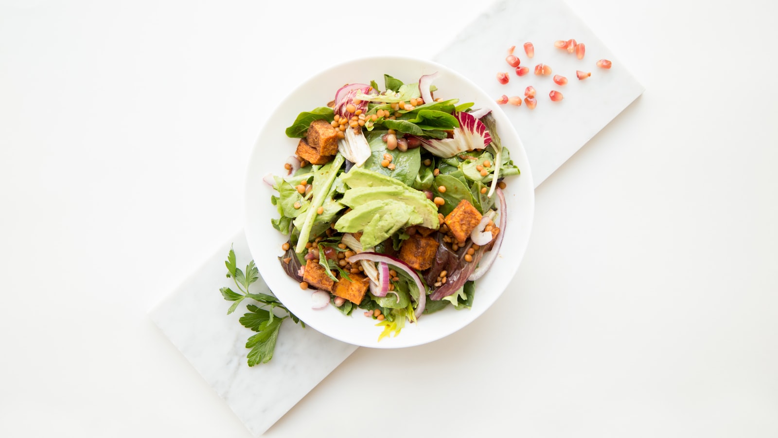 An overhead view of fresh vegetables, grains, and a portion of protein laid out on a counter for cooking